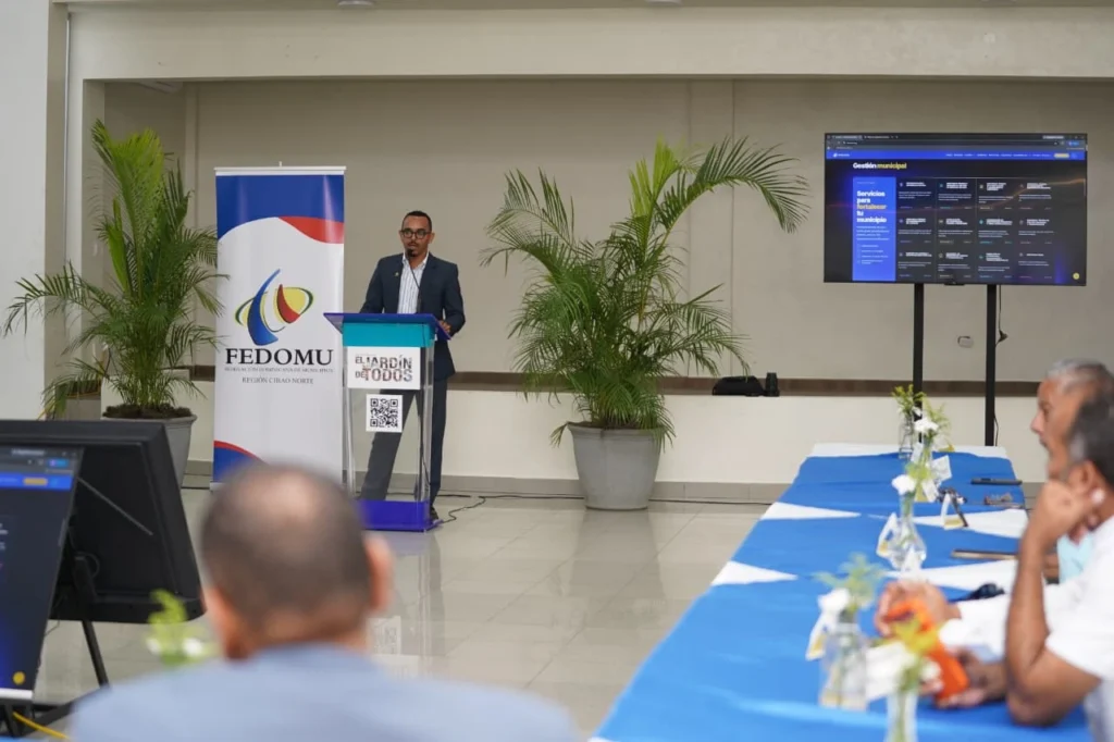 Roberto Valentín Guerrero en el atril junto a una pantalla con el portal de servicios de Fedomu