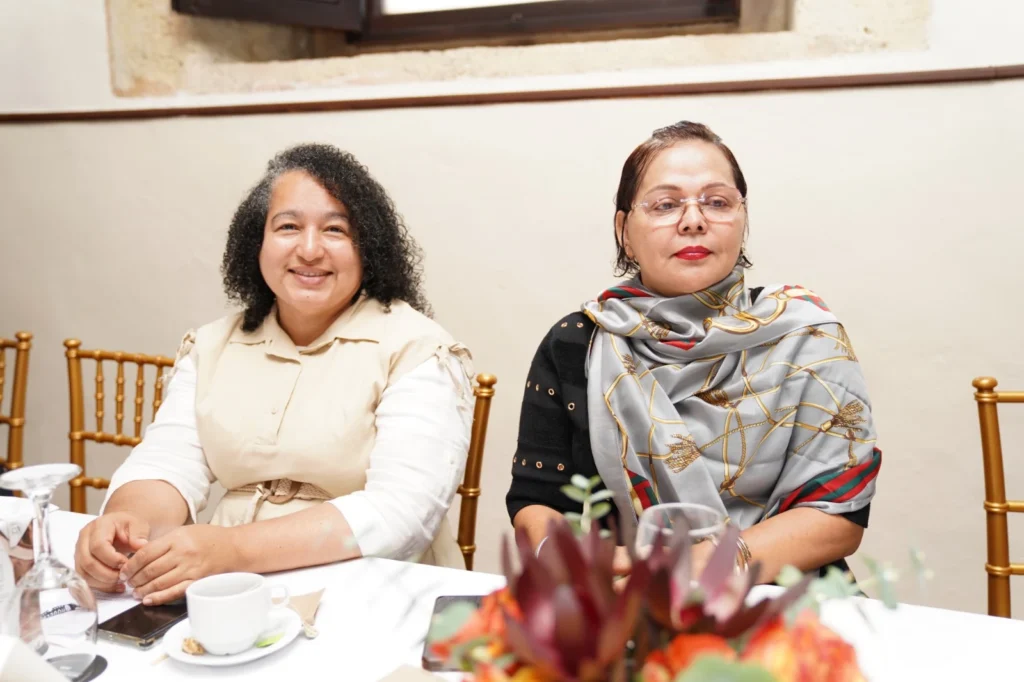 Yissell Santana y Emérita Peña sentadas a la mesa durante la asamblea