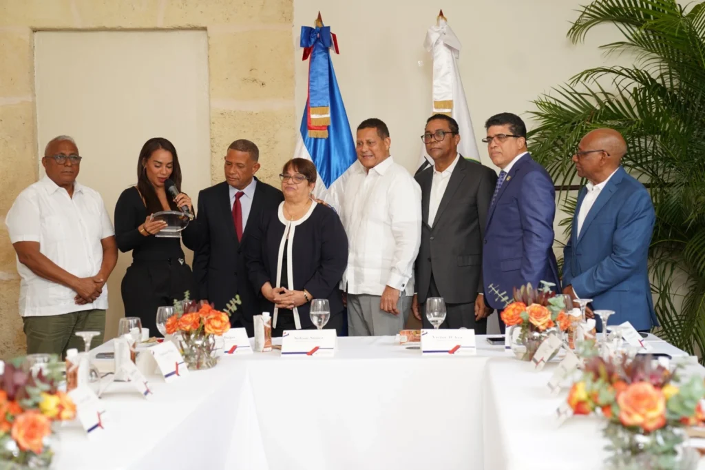 Sergia Santiago de pie en la mesa principal junto a César Rojas, Nelson Núñez y Dio Astacio mientras se lee la placa