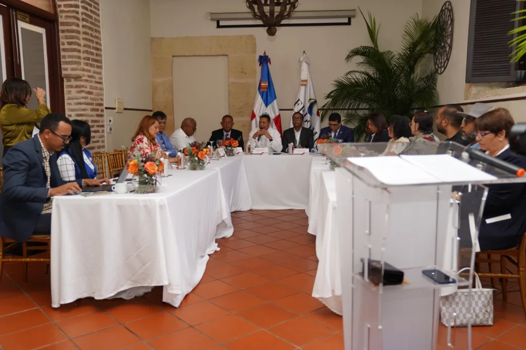 Alcaldes, alcaldesas e invitados sentados alrededor de una mesa en forma de U durante la asamblea