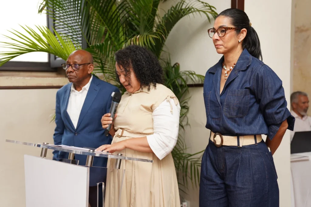 Félix Santos, Yissell Santana con el micrófono en el atril y Wanda Alfau, de pie